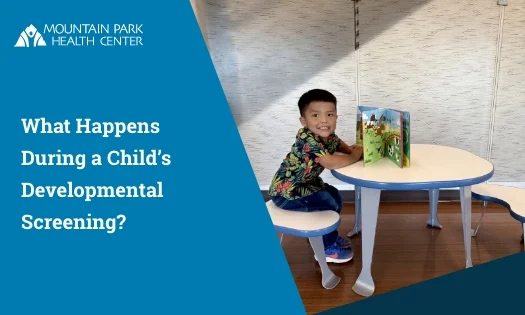 Child seated at a small table with an open picture book in a clinic room.
